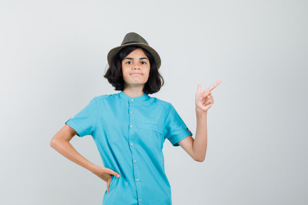 优雅穿蓝衬衫的年轻女士 帽子指向一边指向时尚看