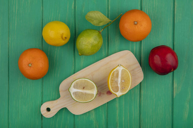 绿色在绿色背景的砧板上俯瞰橘子和柠檬柠檬彩色橙色