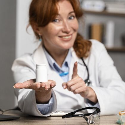 职业微笑女医生提供一瓶药的正面图医生工作医疗