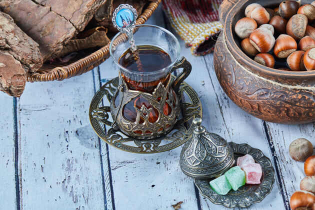 桌子红茶放在传统的玻璃杯子里 蓝色的木桌上放着糖果和一碗榛子木头糖果刷新