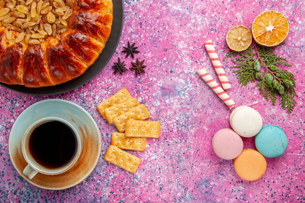 烘焙顶视图美味的糕点蛋糕葡萄干茶麦卡龙饼干在粉红色的桌子上蛋糕派糖