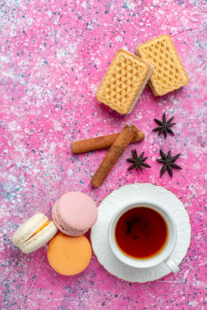 蛋糕在浅粉色的桌子上 可以俯瞰一杯茶 里面放着法国马卡龙和饼干饼干茶法式