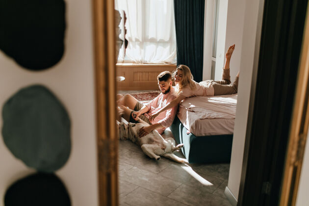 成人一对情侣在阳光明媚的卧室里和拉布拉多玩耍的周末照片男孩和女孩正在抚摸大狗的肚子团聚公寓在一起