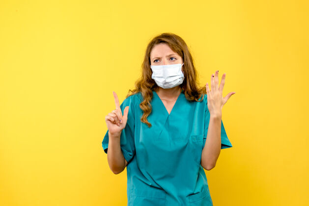脸黄色空间里戴着面具的女医生的正视图冠状病毒医学视图