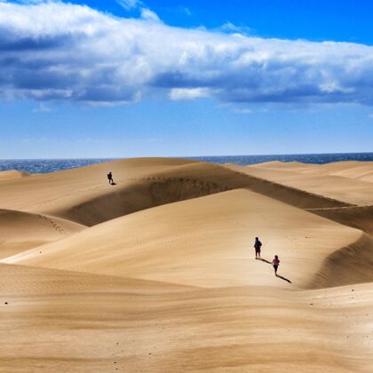 沙子一群人在多云的天空下走过沙丘热路线云