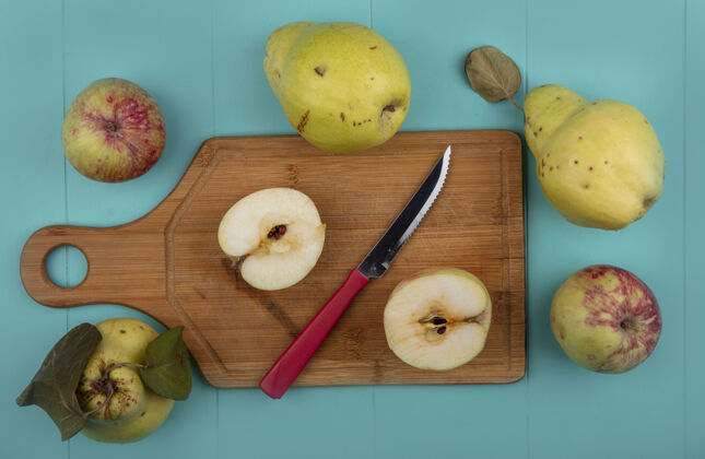 木瓜在木制厨房板上看到新鲜的苹果被切成两半 刀上的木瓜被隔离在蓝色的背景上蓝色视野苹果