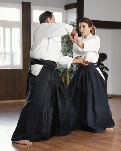柔道男武术指导员和女学员在练习厅训练的侧视图女人战斗教练