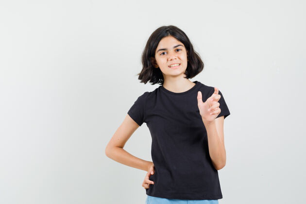 和平穿黑色t恤 短裤的小女孩 展示小尺寸标志 正面看起来很正面小人成人