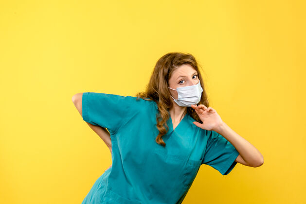 人物黄色空间里戴着面具的女医生的正视图冠状病毒大流行女医生
