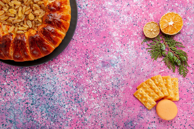 烘焙在粉红色的桌子上俯瞰美味的葡萄干和饼干糕点食物派糖