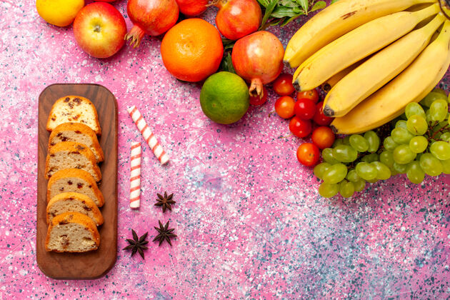 农产品俯瞰美味的水果组成与切片蛋糕在粉红色的办公桌上新鲜苹果蛋糕