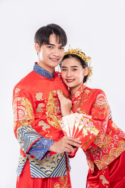 女孩在传统节日里 男人和女人穿旗袍 并展示来自家庭的红色礼金男孩人民庆祝