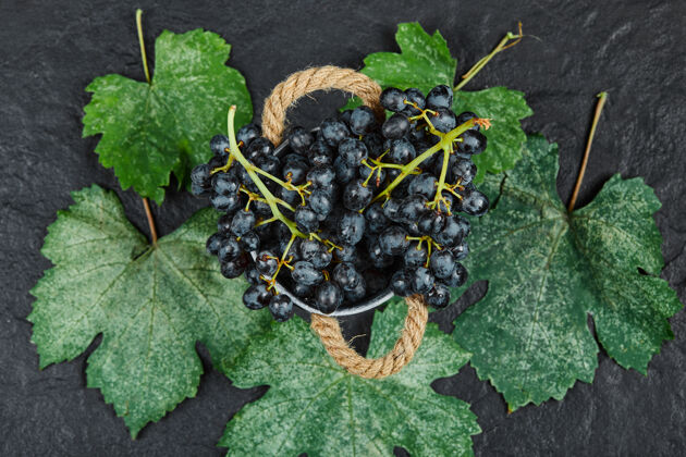 健康一桶黑葡萄的顶视图 黑色表面有叶子正面视图多汁一串