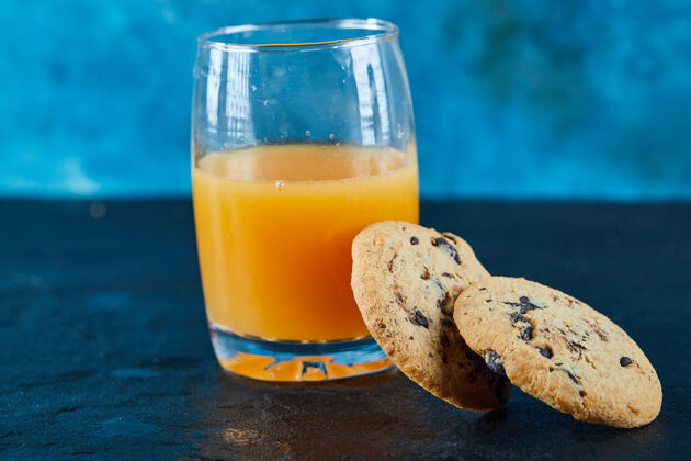 饼干黑桌子上有巧克力片饼干和一杯橙汁美食果汁食品