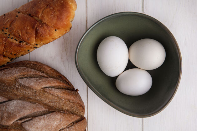 黑顶视图鸡蛋在碗和面包的黑色和白色的背景上白色鸡蛋白碗
