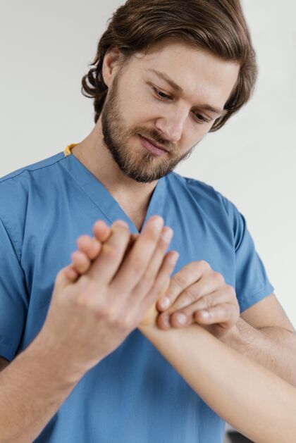医生男性骨科治疗师检查女性患者手腕的前视图男人肌肉骨骼运动