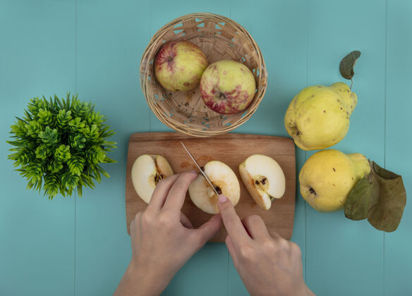 蓝色俯视图中的女性手切割新鲜的苹果在木制厨房板上与刀蓝色背景视图手苹果