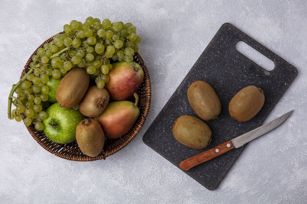 切顶视图猕猴桃与一个绿色的苹果 葡萄和梨子在一个篮子在一个白色的背景刀白色新鲜篮子