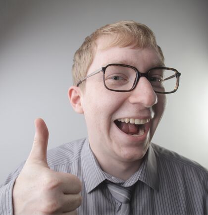 肖像一个年轻的白人男性穿着衬衫和领带愉快的脸印象-概念：快乐脸领带竖起大拇指