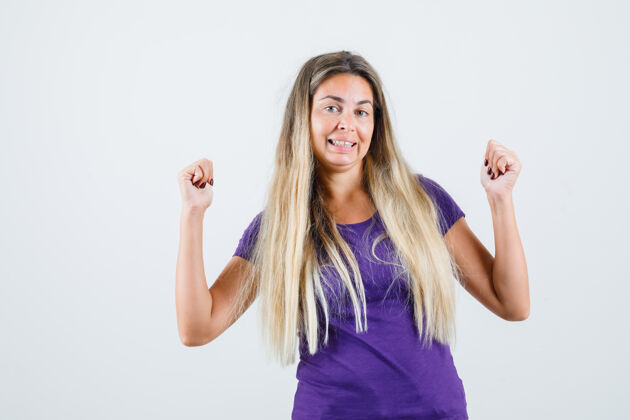 可爱一位金发女士穿着紫罗兰色的t恤展示着赢家的姿态 看上去很幸福正视图魅力女人成人