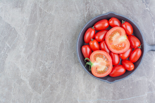 可口在一个黑色的平底锅里放一个红色的全切和半切的樱桃番茄蔬菜甜味新鲜