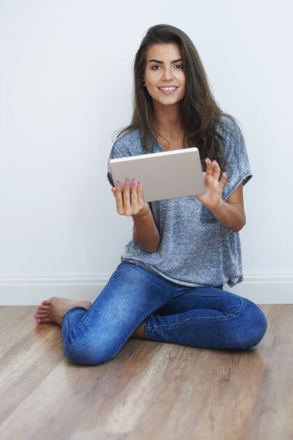 深色头发美女使用数码平板电脑全身木地板自然