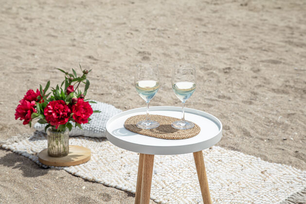 浪漫带着鲜花和香槟的野餐度假的概念饮料浪漫沙子