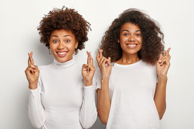 单色两位美国黑人女学生手指交叉 相信好运和考试取得优异成绩 开心地微笑人类学生关系