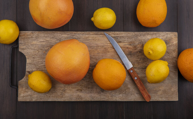橘子在木制背景上用刀在砧板上俯瞰柠檬 橙子和葡萄柚柠檬观点食品