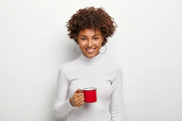 高领毛衣美丽满足的黑皮肤少年拿着红色杯子和热饮料咖啡浓缩咖啡享受