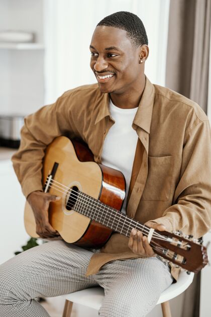 音乐家笑脸男音乐家在家弹吉他的正面图男性人才乐器