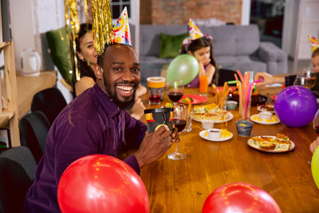 一起快乐的多民族家庭在家里庆祝生日的画像大家庭一边吃零食一边喝葡萄酒 一边问候和款待孩子庆祝 家庭 聚会 家的概念女儿气球健康