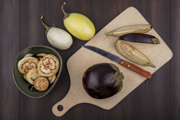 切片顶视图黑色茄子在砧板上与刀和切片在碗在木制背景上黑食物烹饪