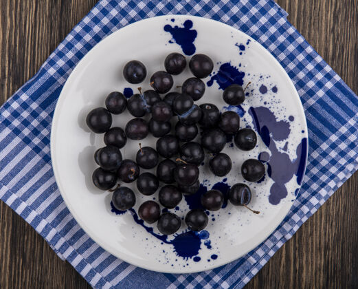 李子顶视图樱桃李子在一个蓝色格子毛巾上的白色盘子水果格子风景
