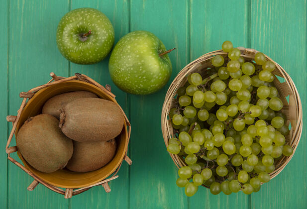 多汁顶视图猕猴桃与绿色的葡萄在篮子和绿色的背景上的绿色苹果葡萄苹果食品
