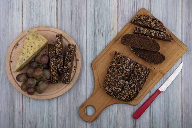 面包房顶视图黑色面包与一个灰色背景上的葡萄和奶酪的立场上的董事会刀面包食物木板