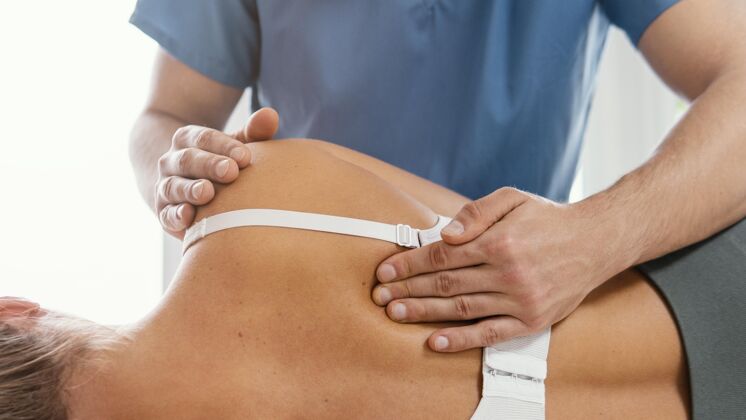 病人骨科治疗师检查女性患者背部的前视图运动水平骨病
