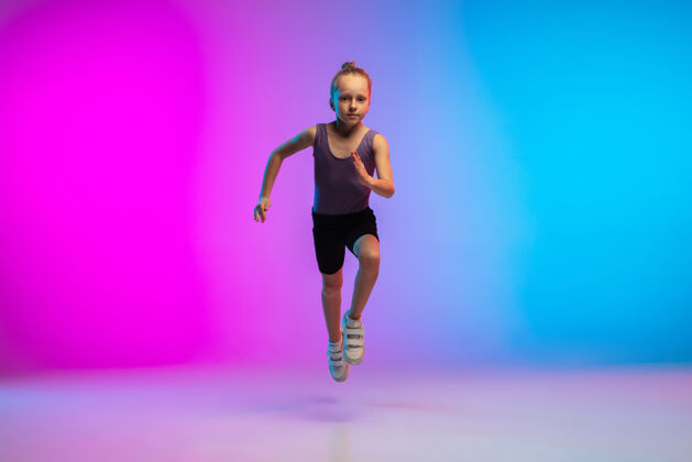 进步健康少女 专业跑步者 慢跑者 在霓虹灯下的渐变粉蓝色背景上运动隔离运动 运动 活力和动态的概念 健康的生活方式儿童比赛年轻