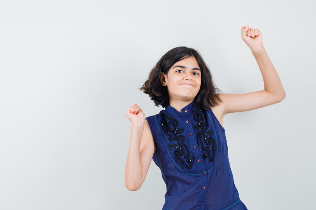 青少年一个穿着蓝色上衣的小女孩表现出胜利的姿态 看起来很幸福和平年轻光