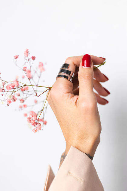 浪漫柔美温柔的照片 女人手上戴着大戒指 红色的指甲 手上拿着可爱的粉色干花茎新鲜美丽