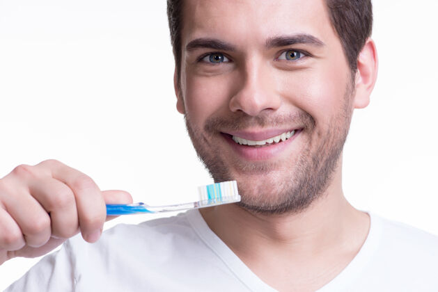 微笑？？？一个戴着牙刷的快乐的年轻人的失传肖像-孤立在白色上成人帅哥牙齿