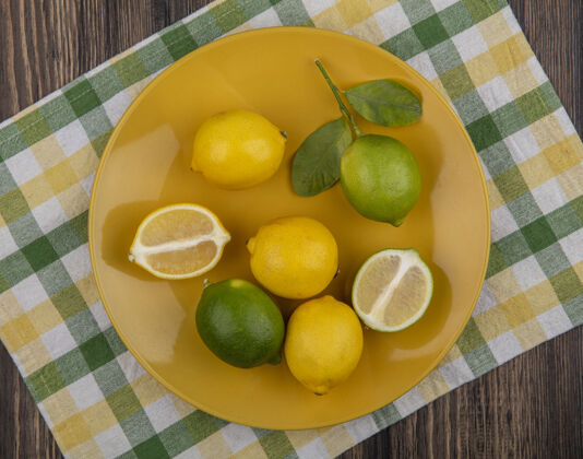 食物在黄绿色格子毛巾上的黄色盘子上俯瞰柠檬和酸橙盘子格子风景