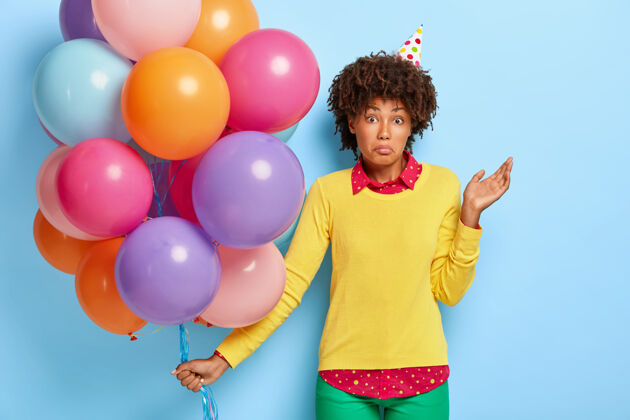 魅力困惑不解的非洲女人拿着彩色气球站着 不知道聚会在哪里举行头发不知道周年纪念