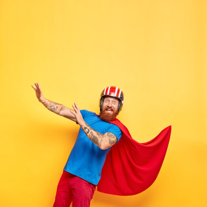 胡须滑稽开朗的男超级英雄戴着头盔和红色斗篷男性吓人强壮