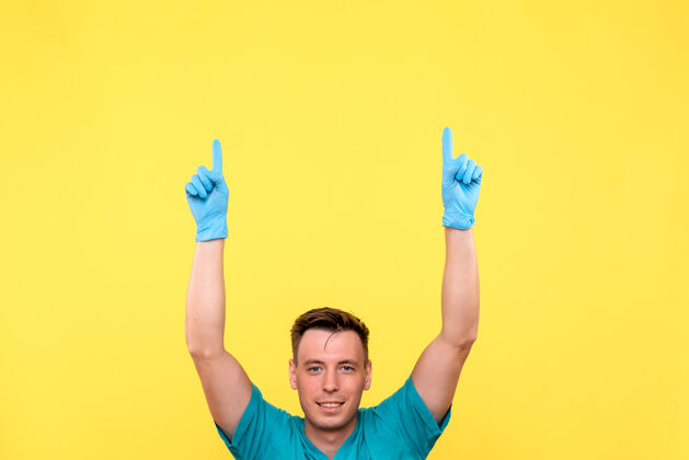 黄色黄墙上男医生戴着蓝手套摆姿势的正面图漂亮欢呼医院