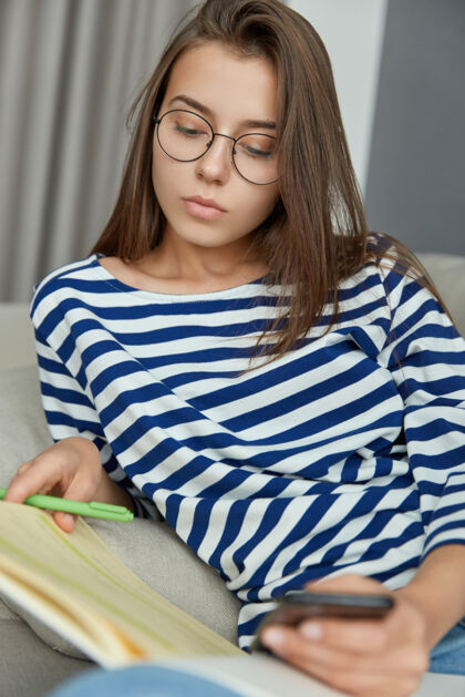 电话照片集中的女性读者看书 用笔强调信息 努力丰富词汇量 手持现代手机 戴眼镜视力好 表情严肃阅读学习短信