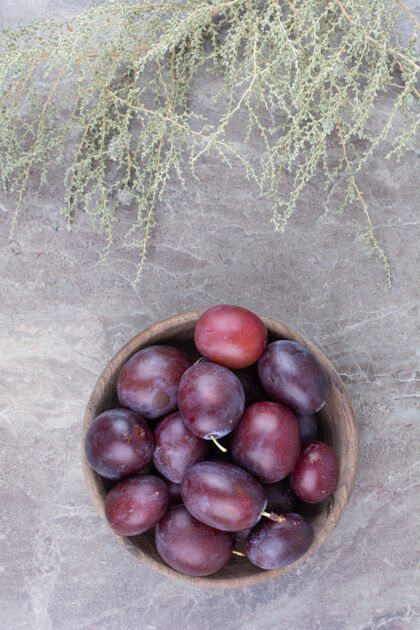 新鲜在石头背景上的木碗里放上新鲜的李子李子水果紫色