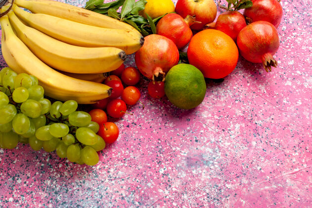 醇香正面是黄色的新鲜香蕉 粉红色的桌子上有葡萄和石榴的美味水果异国情调生的维生素