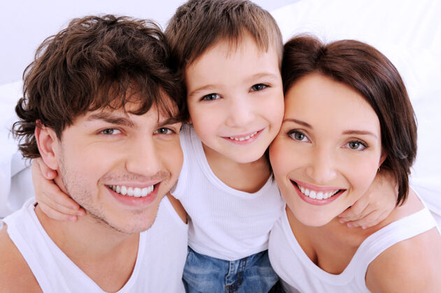快乐美丽的笑脸一个幸福的年轻家庭由三个人组成爸爸拥抱高角度
