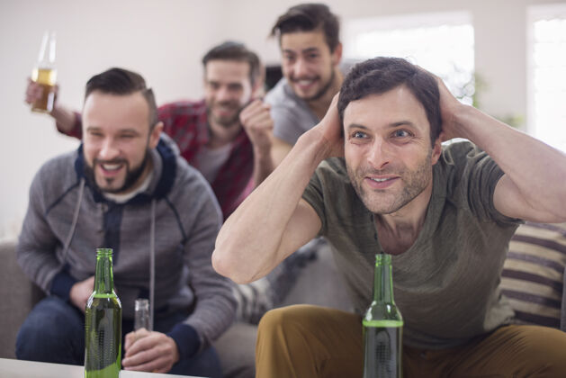 支持朋友们喝啤酒看足球赛目标啤酒瓶看电视